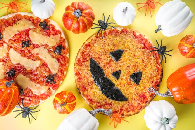 Truc ou friandise de fête d'Halloween, pizza effrayante amusante dans le style des personnages d'Halloween - chauves-souris, araignées, citrouille jack o lantern, cheddar, mozzarella et fromage noir