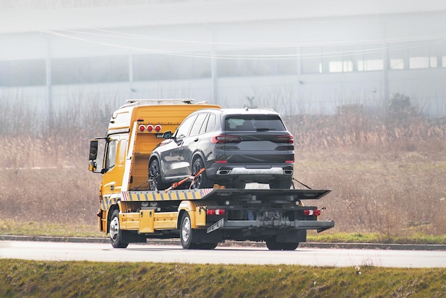 Photo truck de remorquage à plat avec une voiture sur la route assistance routière concept de transport de service de voiture
