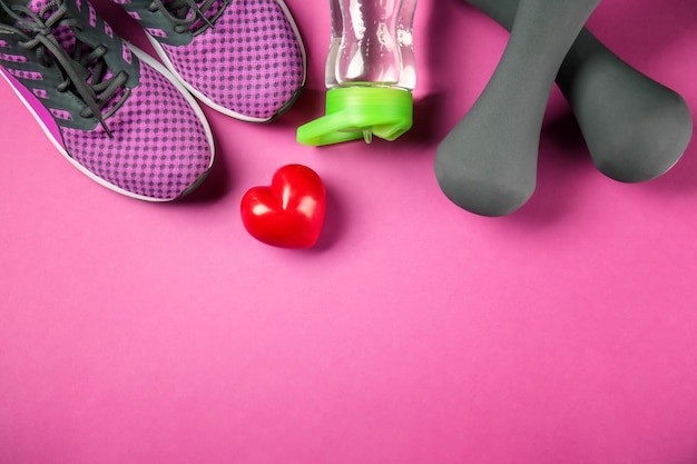 Trucs de gym et coeur rouge sur fond de couleur Concept d'entraînement cardio