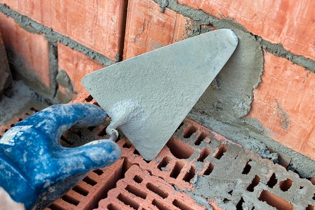 Truelle de construction pour la pose de briques et de blocs Outil de construction d'un maçon Outil de travail à la main sur le fond de la maçonnerie