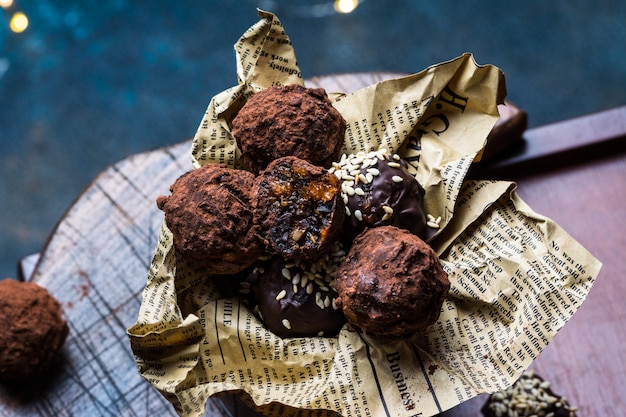 Truffe aux bonbons au chocolat avec des morceaux de chocolat et de la poudre de cacao volant sur un fond sombre. Bonbons sains. Bonbons végétaliens. Dessert du Nouvel An. Dessert de Noël. La Saint-Valentin