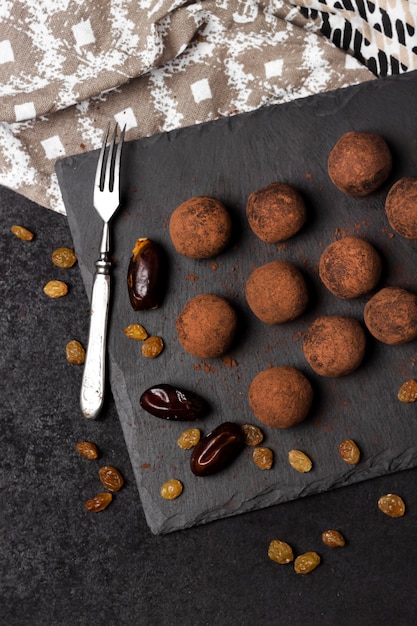 Truffes végétaliennes faites maison avec des fruits secs, des noix et de la poudre de cacao crue servies sur une plaque en ardoise noire