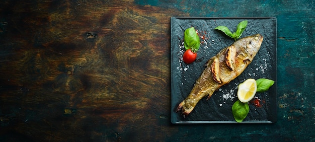 Truite cuite au four avec citron et légumes sur une assiette en pierre noire Fruits de mer Poisson de rivière Vue de dessus