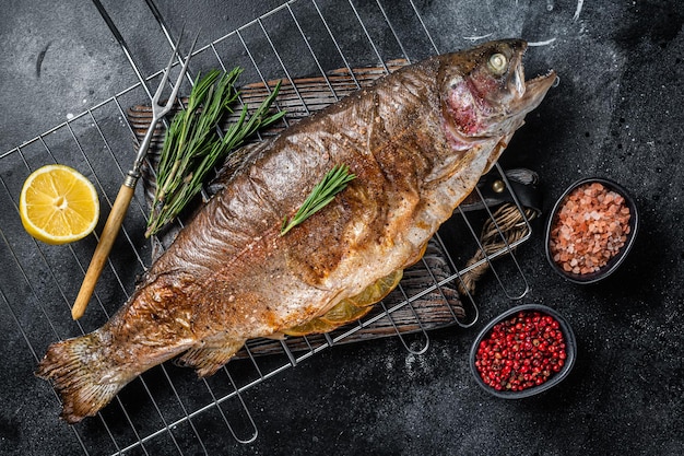 Truite de mer rôtie au barbecue Poisson grillé sur un gril au romarin Fond noir Vue de dessus