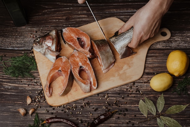 Truite sur le plateau, qui coupe un homme cuisiner avec un couteau, poisson rouge cru frais