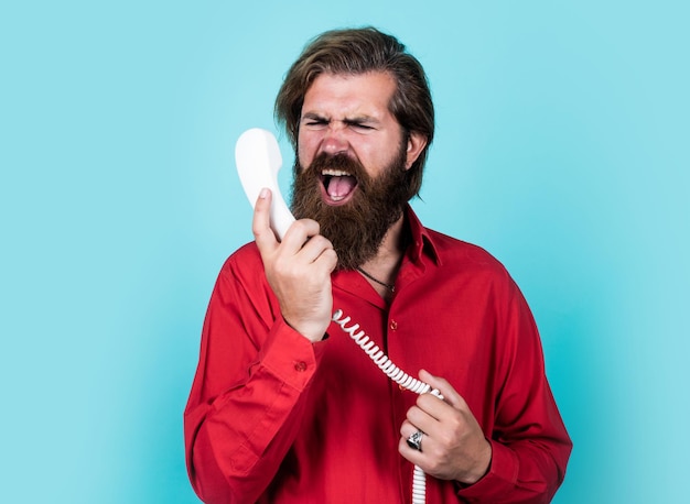 Tu me mets en colère. parler avec un ami au téléphone. un homme mature tient un téléphone rétro. gars avec barbe et moustache répondant à l'appel. conversation téléphonique. homme barbu. communication dans la vie moderne.