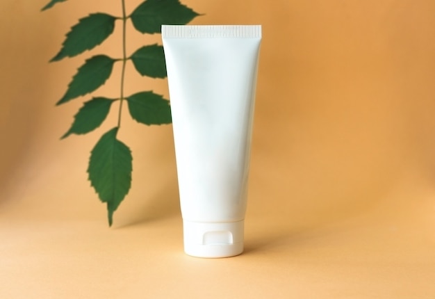 Tube blanc de crème avec des feuilles vertes concept de beauté cosmétique spa bio naturel