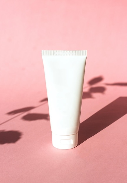 Tube blanc en plastique pour crème sur fond rose avec produit écologique cosmétique ombre