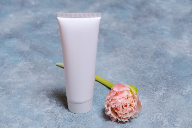 Tube cosmétique blanc et fleur de tulipe rose sur fond bleu Concept