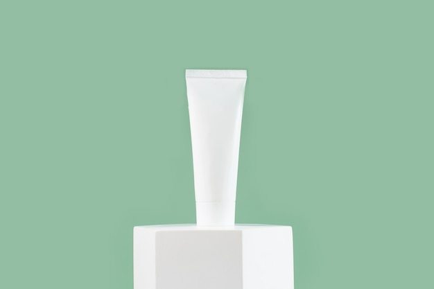 Tube cosmétique blanc pour le corps du visage de soins de la peau sur podium blanc sur fond vert