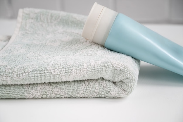Le tube cosmétique repose sur une serviette fraîche sur la table de la salle de bain