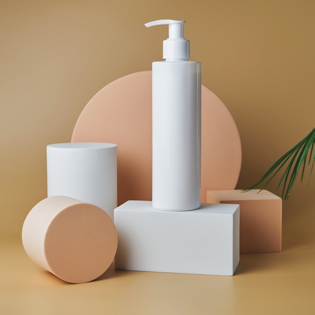 Tube de cosmétiques à la mode avec crème sur piédestal à la surface beige avec feuille de palmier