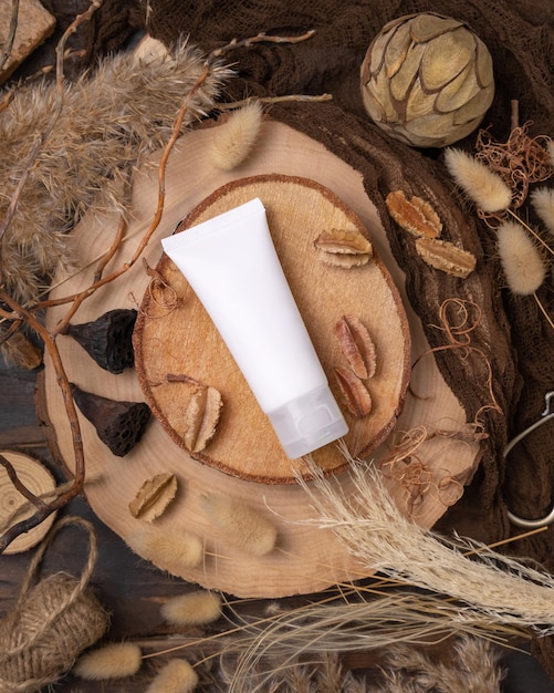 Tube de crème en plastique blanc sur bois près de décorations naturelles vue de dessus Emballage cosmétique Maquette