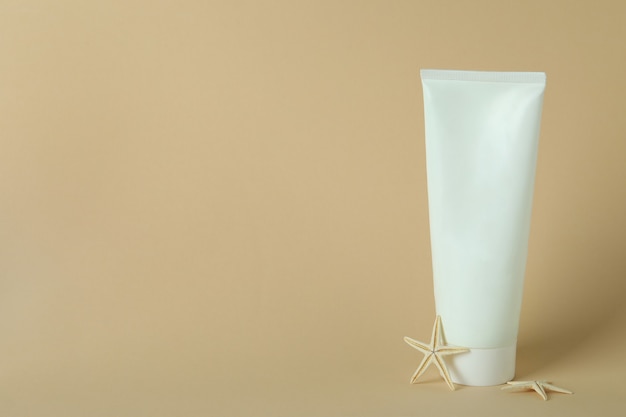 Tube de crème solaire et étoiles de mer sur fond isolé beige