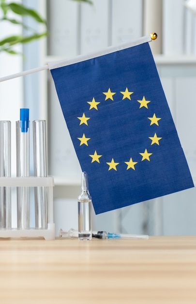 Tube à essai, ampoule, seringue et drapeau de l'Union européenne, concept de vaccination mondiale.