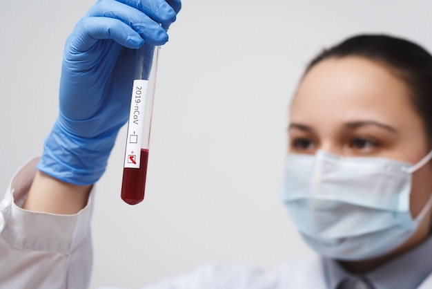 Tube à essai sanguin dans la main du médecin, test du coronavirus Mers-CoV Étiquette positive dans le tube à essai sanguin de l'hôpital pour analyse. Infection par le virus nCoV 2019