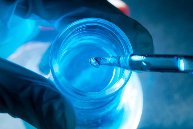 Photo tube à essai scientifique bleu, flacon dans la main du scientifique avec goutte de liquide chimique dans le tube à essai