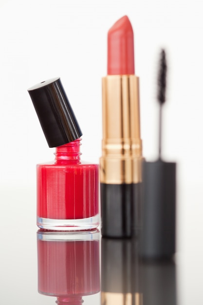 Un tube de mascara avec un rouge à lèvres rouge pâle et un flacon de vernis à ongles rouge