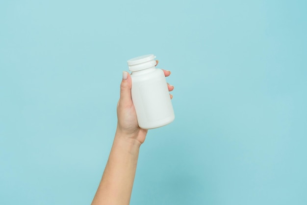 Tube en plastique blanc dans une main féminine Bouteille pour capsule de pilule ou supplément Maquette de marque de produit