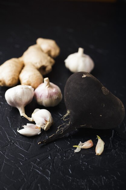 Tuber radis noir et ail sur une surface de béton noir