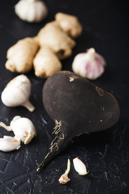 Tuber radis noir et ail sur une surface de béton noir