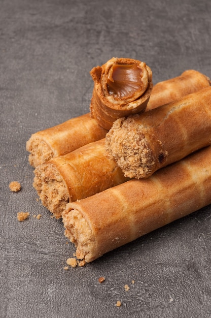 Tubes à gaufres avec du lait concentré bouilli sur fond gris