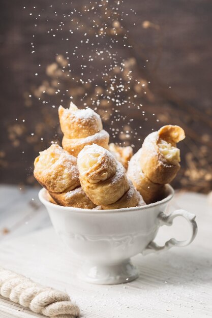 Tubes de pâtisserie avec crème fouettée dans la tasse blanche