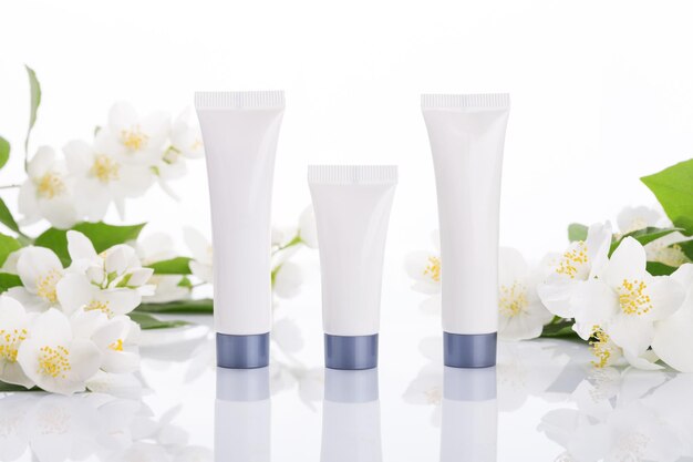 Tubes vides de crème sur fond blanc avec des fleurs