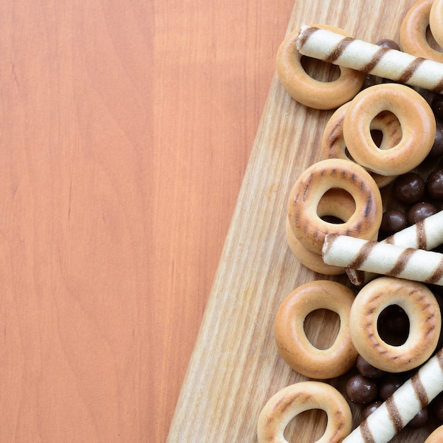 Des tubules croustillants, des boules de chocolat et des bagels reposent sur une surface en bois