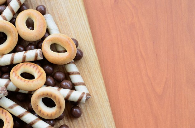 Des tubules croustillants, des boules de chocolat fondant et des bagels reposent sur une surface en bois. Mélange de bonbons divers