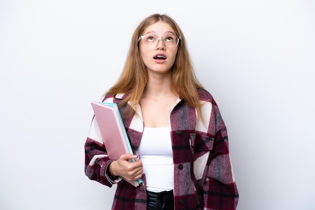 Étudiant adolescent fille russe isolé sur fond blanc en levant et avec une expression surprise