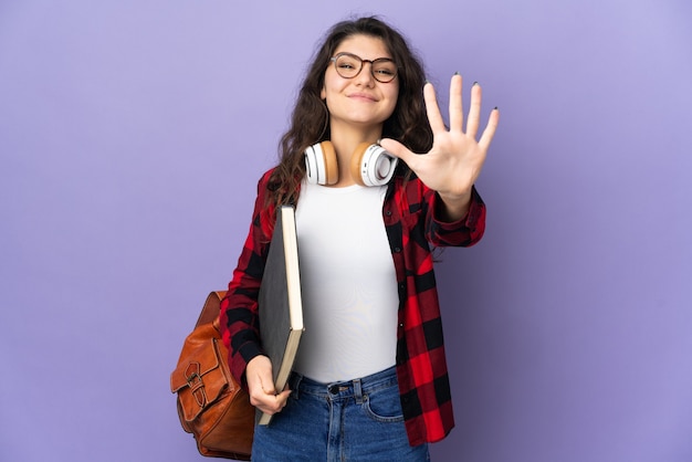 Étudiant adolescent isolé sur mur violet comptant cinq avec les doigts