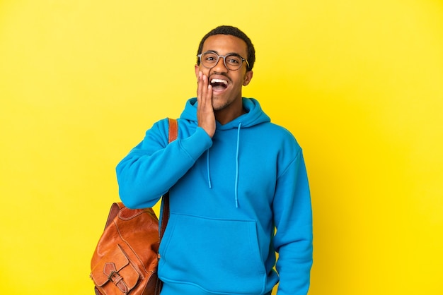 Étudiant afro-américain sur un mur jaune isolé avec une expression faciale surprise et choquée