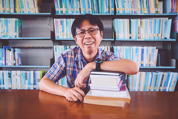 Étudiant asiatique s'ennuie avec des livres dans la bibliothèque