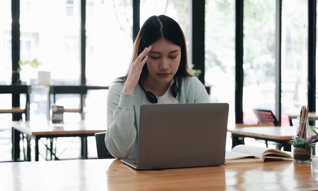 Étudiant asiatique sérieux et concentré utilisant un ordinateur portable dans la cuisine en regardant l'écran avec attention et concentration en regardant l'apprentissage du cours vidéo de formation virtuelle sur le webinaire étudiant à la maison