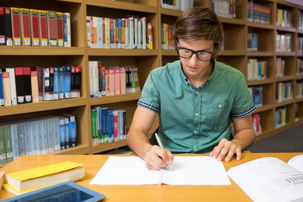 Étudiant assis dans l&#39;écriture de la bibliothèque