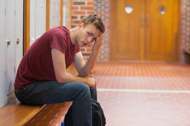 Étudiant beau fronçant ayant un mal de tête