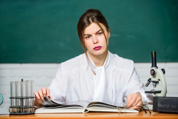 Étudiant en biologie assis sur fond de tableau en classe Étudiant intelligent Étudier dur Recherche scientifique Concept d'éducation Femme assez adorable enseignant ou étudiant Biologiste chimiste avec microscope