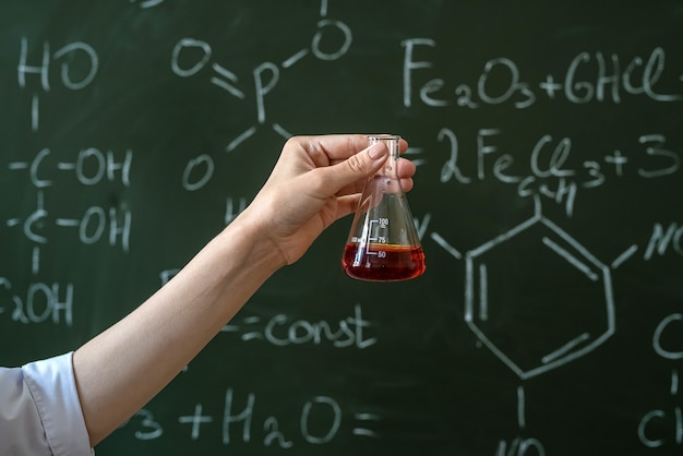 Étudiant en blouse blanche faisant un test expérimental en laboratoire de chimie avec formule liquide, éducation