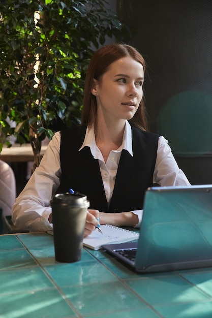 Étudiant caucasien assis à table de café étudiant avec ordinateur portable à faire ses devoirs