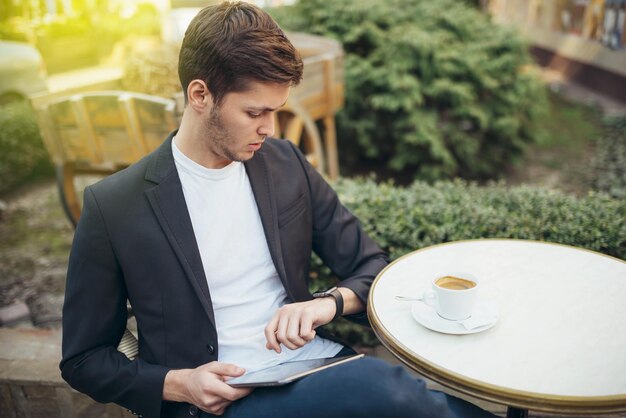 Étudiant caucasien élégant surfant sur Internet sur une tablette numérique bénéficiant d'une connexion sans fil gratuite au café pendant la pause-café Messagerie indépendante masculine en ligne Concept de technologie et de communication