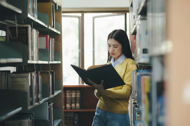 Étudiant debout et lisant un livre à la bibliothèque