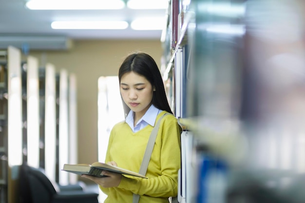 Étudiant debout et lisant un livre à la bibliothèque