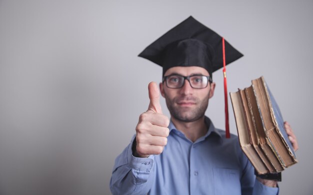 Étudiant diplômé tenant des livres au bureau.