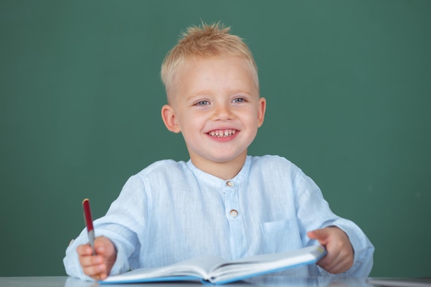 Étudiant de l'école apprendre la leçon assis à un bureau en train d'étudier l'écriture d'un enfant dans un cahier en éducation de classe