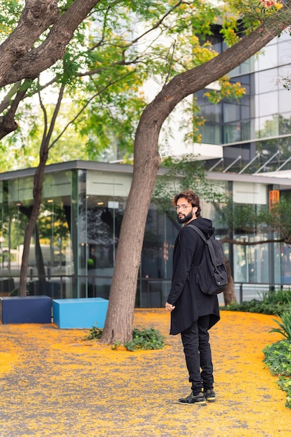 Étudiant élégant marchant avec un sac à dos sur le campus