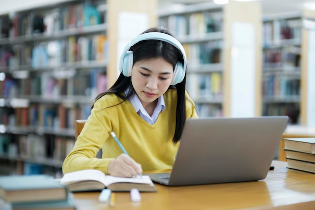 Étudiant étudiant à la bibliothèque avec ordinateur portable