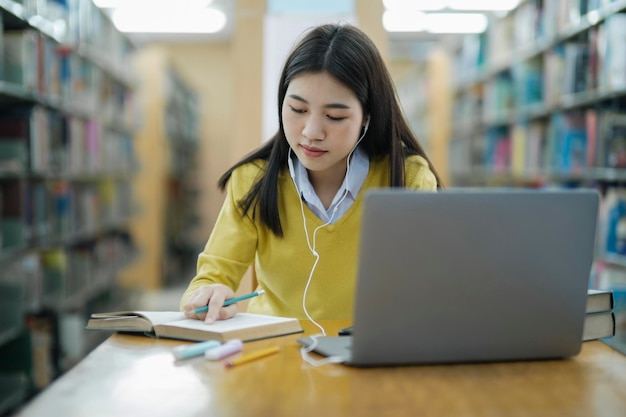 Étudiant étudiant à la bibliothèque avec ordinateur portable