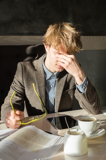 Étudiant fatigué décolle de lire des lunettes et se frotte les yeux pendant la pause-café au restaurant