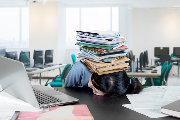 Étudiant fatigué avec une pile de livres